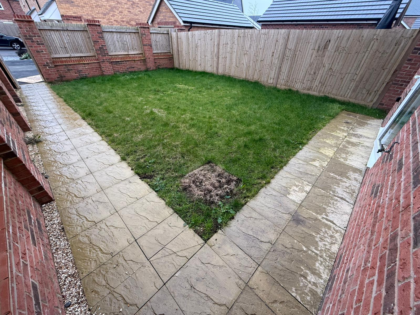 New-build garden before work with patchy lawn and dated paving slabs