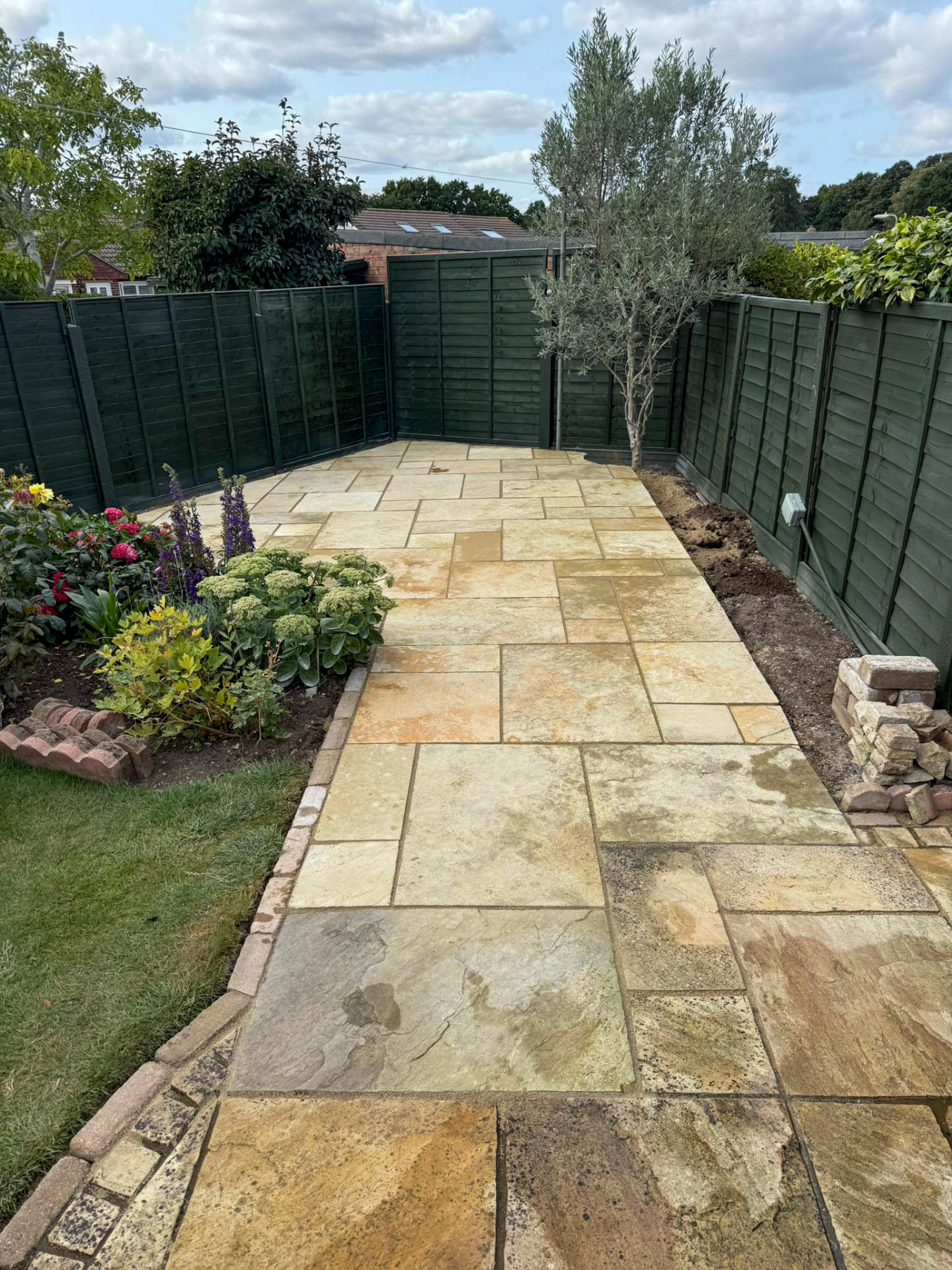 Finished Indian sandstone patio with brick edging and planted borders